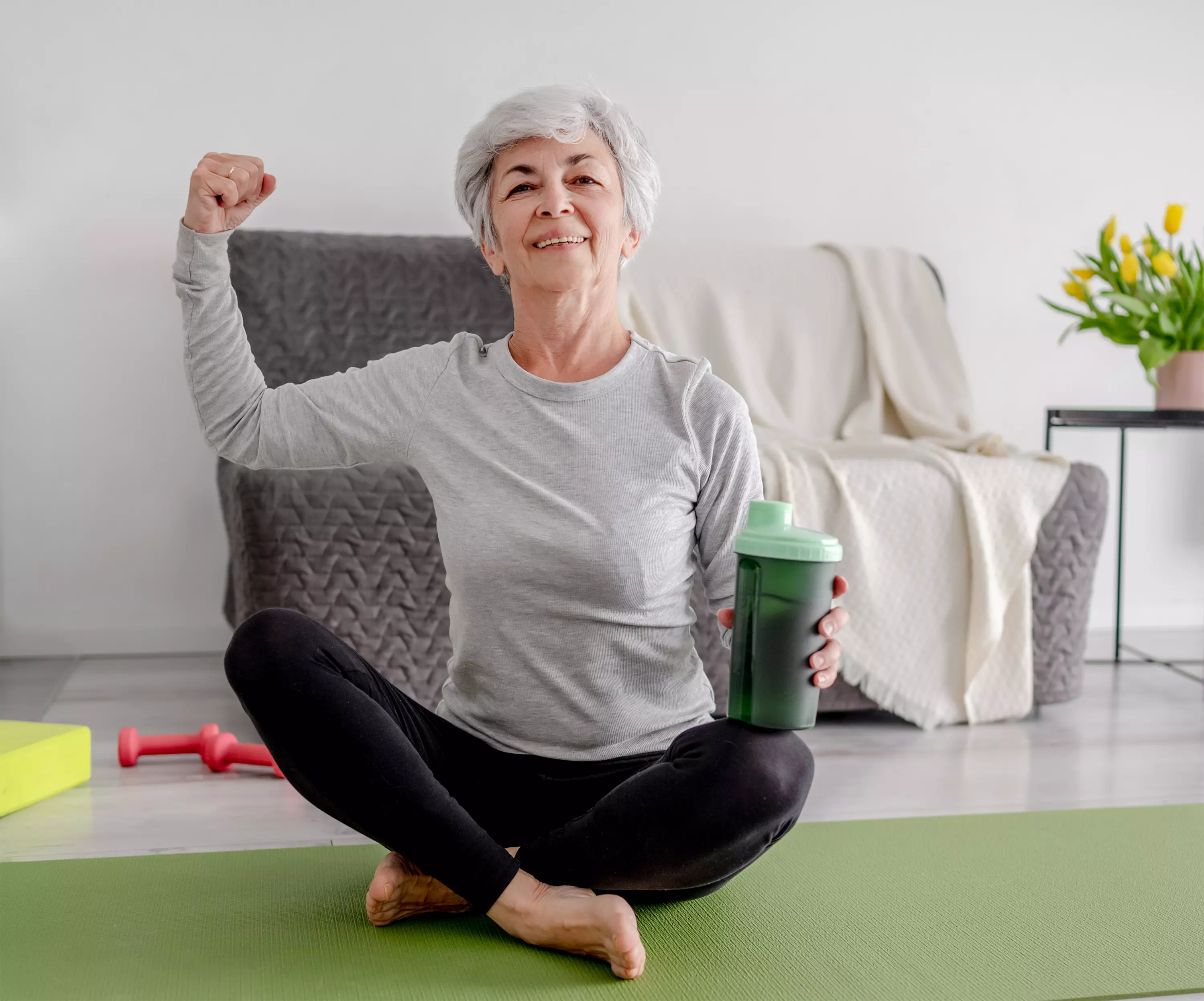 strong woman sitting on yoga mat with smoothie