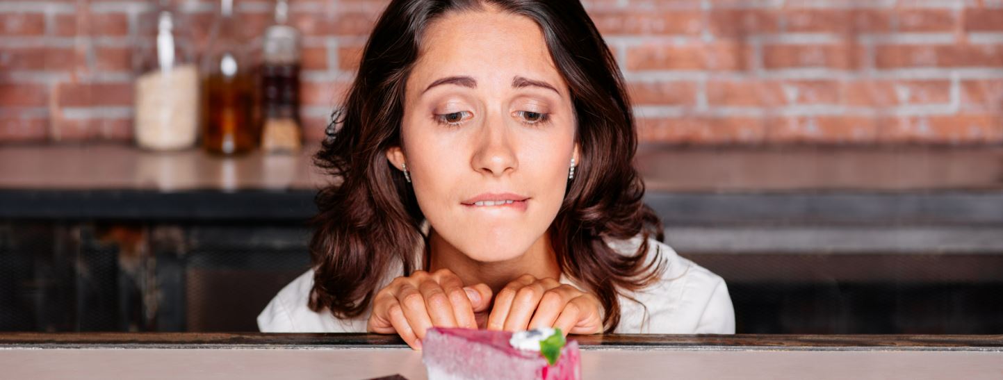 Woman trying to resist sugary dessert